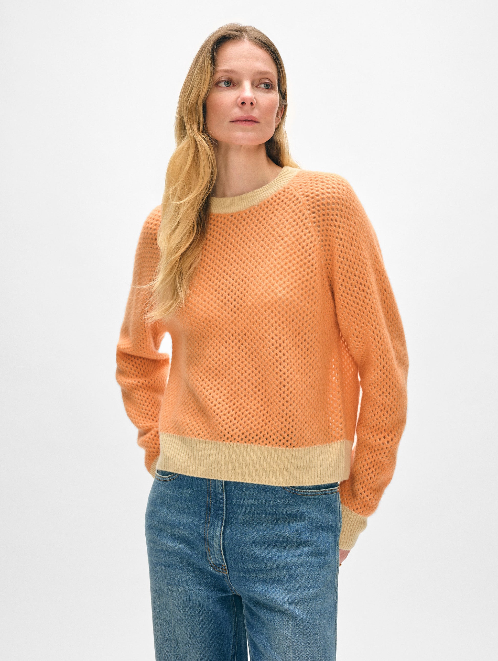 Model wearing bright orange cashmere crewneck sweater.